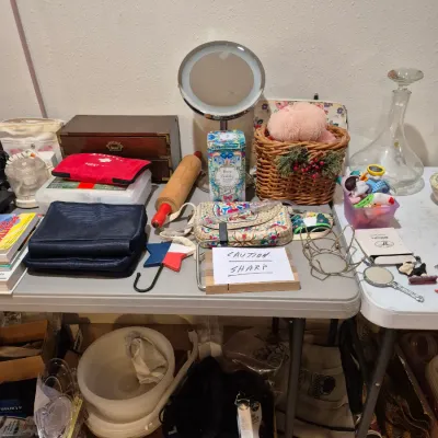 Sale Photo Thumbnail #11: Tabletop assortment of household goods, including a lighted makeup mirror, a wooden jewelry box, a rolling pin, a glass decanter, and various small accessories.