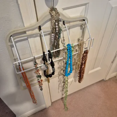 Sale Photo Thumbnail #63: Collection of costume jewelry necklaces hanging from a white metal door organizer, featuring beaded, metallic, and statement styles.