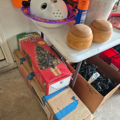 Sale Photo Thumbnail #30: Collection of seasonal decor and household items, including a boxed 32-inch fiber optic tree, Halloween white mask, wooden containers, and string lights.