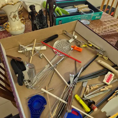 Sale Photo Thumbnail #19: Cardboard flat filled with assorted vintage and modern kitchen utensils, gadgetry, and wooden skewers.