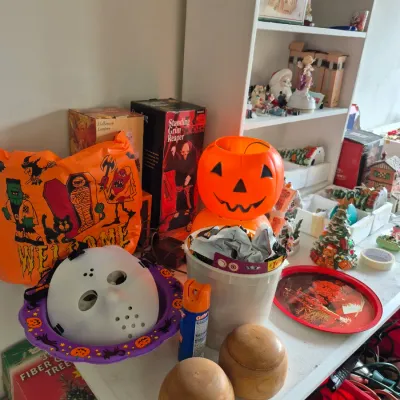 Sale Photo Thumbnail #31: Collection of assorted Halloween and Christmas holiday decorations, including a plastic jack-o'-lantern, hockey mask, inflatable sign, and boxed seasonal items.