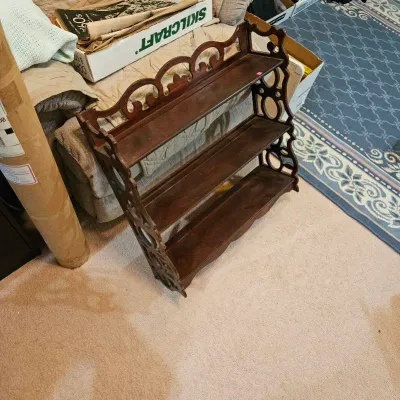 Vintage dark wood three-tiered wall shelf featuring ornate scrollwork top and pierced cut-out side panels.