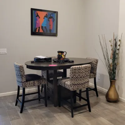 Contemporary dark wood counter-height dining set with four ikat patterned upholstered chairs, accompanied by framed artwork and a...