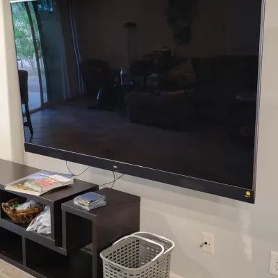 Large wall-mounted TCL flat screen TV displayed above a black modular media console.