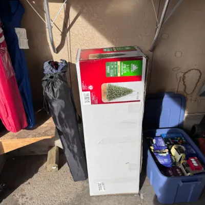Sale Photo Thumbnail #11: Enchanted Forest 6-1/2 foot Pre-Lit Renaissance Pine hinged Christmas tree in original box, sitting alongside portable folding chairs and a blue plastic tote filled with Christmas light sets.