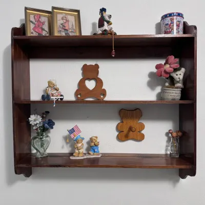 Sale Photo Thumbnail #26: Vintage dark stain wooden three-tier wall hanging display shelf unit holding various small teddy bear collectibles, framed pictures, and decorative knick-knacks.