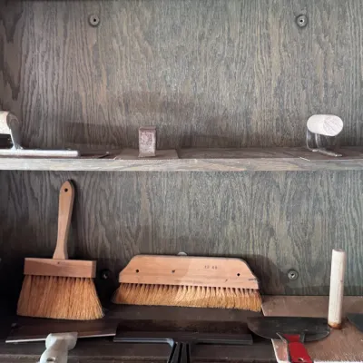 Sale Photo Thumbnail #8: Assortment of drywall, plaster, and masonry hand tools, including concrete floats, hand brushes, and putty knives, neatly arranged on wooden shelving.