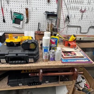 Sale Photo Thumbnail #48: DeWalt 18V cordless drill with hard case and rechargeable batteries, arranged on a workbench alongside aerosol spray cans, Oatey PVC cement, and various workshop tools.