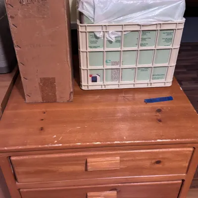 Sale Photo Thumbnail #36: Title: Vintage Wooden 3-Drawer Dresser Chest with Cardboard and Plastic Storage Containers. Category: Furniture / Dressers & Storage. Solid pine or honey-oak stained wooden chest of drawers featuring integrated wooden pull handles, showing light surface s