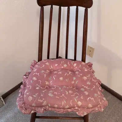 Sale Photo Thumbnail #29: Vintage dark wood spindle-back side chair featuring a curved top crest rail and a pink floral ruffled seat cushion, in solid vintage condition.