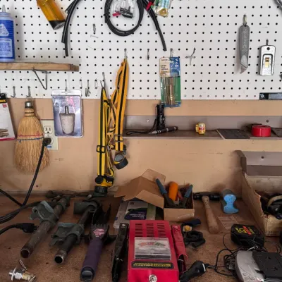 Sale Photo Thumbnail #5: Workshop tools, hardware, and equipment assortment featuring a Chicago Electric battery load tester made in China, pipe clamps, hand tools, and pegboard accessories.