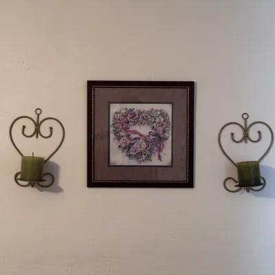 Sale Photo Thumbnail #25: Framed floral heart art print featuring pink roses and ribbons, flanked by a pair of vintage heart-shaped wrought metal wall sconces with green pillar candles.
