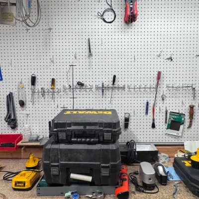 Sale Photo Thumbnail #47: DeWalt Power Tool Cases and Accessories Workbench Setup. Category: Tools & Home Improvement / Power Tools. Stacked black DeWalt hard plastic tool carrying cases sitting on a workshop bench alongside a DeWalt battery charger, hand tools, and a pegboard org