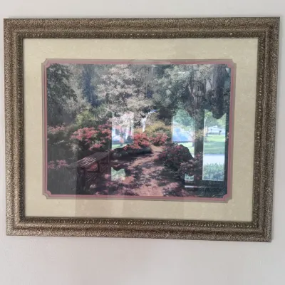 Sale Photo Thumbnail #20: Framed garden landscape print depicting a wooden bench along a sunlit pathway surrounded by flowering azaleas and lush trees. The piece features double matting in cream and dusty rose tones, set in a textured bronze-finish ornate frame.
