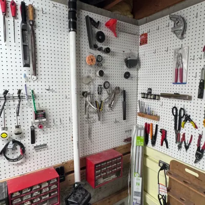 Sale Photo Thumbnail #52: Workshop wall featuring white pegboards organized with various hand tools, pliers, files, and hardware accessories. Includes red multi-drawer small-parts storage organizers and a boxed Feit Electric 4ft LED T8 tube light.