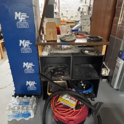 Sale Photo Thumbnail #58: Midwest Fastener Corp. Kalamazoo Michigan blue metal hardware organizer bin tower alongside a Shop-Vac wet/dry vacuum with hose, extension cords, and a rolling wooden utility cart filled with shop supplies.