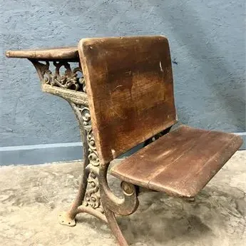 Sale Photo Thumbnail #36: Antique school desk featuring a wooden seat, backrest, and attached desktop supported by ornate cast iron legs.
