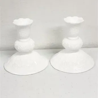 Sale Photo Thumbnail #20: Pair of vintage white milk glass candlesticks with embossed floral patterns and scalloped rims.