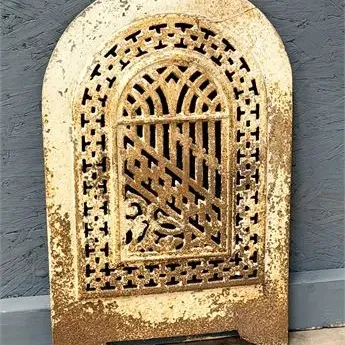 Sale Photo Thumbnail #65: Antique cast iron fireplace insert cover featuring ornate arched fretwork and a distressed, chippy painted finish.