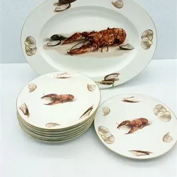 Sale Photo Thumbnail #15: Seafood-themed porcelain service set featuring a large oval serving platter and matching salad plates decorated with lobster, mussel, and clam illustrations.