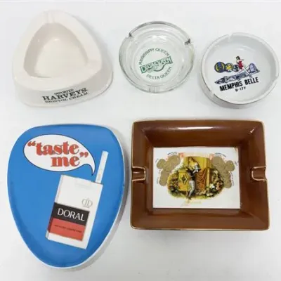 Sale Photo Thumbnail #61: Collection of five vintage advertising ashtrays, featuring designs for Harveys Bristol Cream, Mississippi Queen, Memphis Belle B-17F, Doral Cigarettes, and a cigar brand.