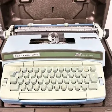 Sale Photo Thumbnail #12: Vintage Smith-Corona Coronet Super 12 Coronamatic electric typewriter in a light blue body, housed inside its original hard plastic carrying case.