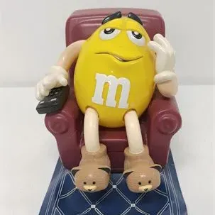 Sale Photo Thumbnail #53: Vintage M&M's collectible candy dispenser featuring the yellow character lounging in an armchair with a remote control.