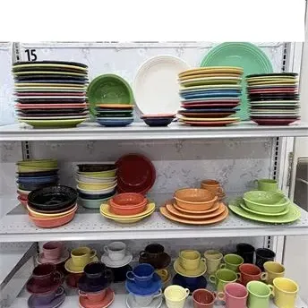 Sale Photo Thumbnail #16: Large collection of colorful vintage Fiestaware ceramic dinnerware organized on retail shelves, including stacks of plates, bowls, and teacups with saucers in various glaze colors.