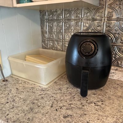 Black Farberware electric air fryer sitting on a granite countertop, in used condition.