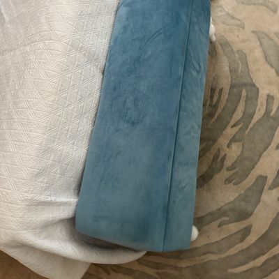 Blue plush velvet upholstered bench featuring white turned wooden legs, positioned at the foot of a bed.