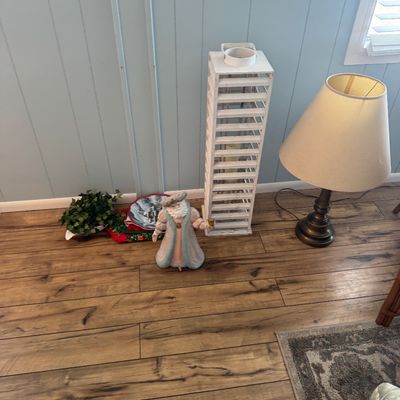 Collection of home decor items featuring a tall white slatted wooden lantern, a traditional Santa Claus figurine in pastel robes, and a...