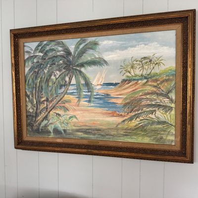 Framed tropical landscape painting featuring palm trees and sailboats on the water, housed in an ornate gilded wood frame.