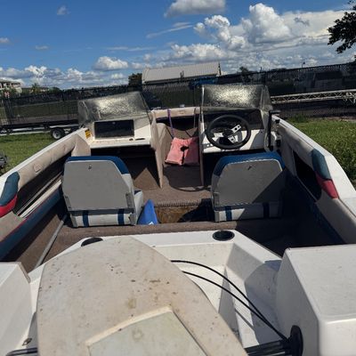 Interior view of a vintage fiberglass speed boat featuring dual windshield consoles, swivel bucket seating, and carpeted deck.