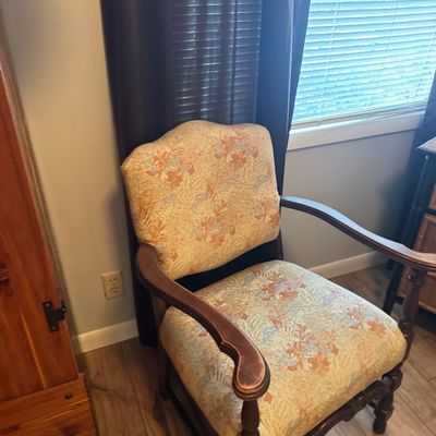 Vintage arm chair featuring floral patterned fabric upholstery and dark wood frame with carved accents.