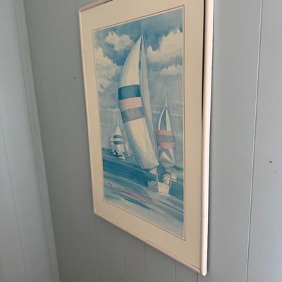 Framed nautical watercolor print featuring sailboats with colorful spinnakers, presented in a light wood frame with a wide cream mat.