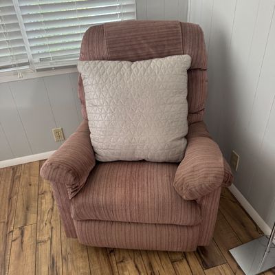 Plush dusty rose striped fabric recliner chair paired with a cream quilted accent pillow.