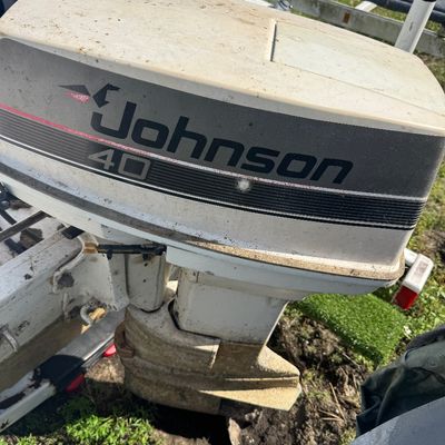 Vintage Johnson 40 HP outboard boat motor attached to a boat stem, showing surface wear and weather exposure.