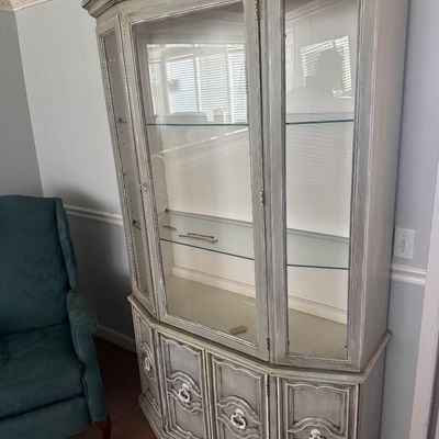 French provincial style whitewashed china cabinet featuring glass display shelves above lower cabinetry.