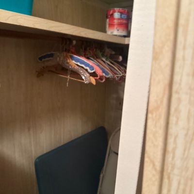 Collection of crocheted and fabric-covered clothes hangers stored inside a wood-panelled closet.