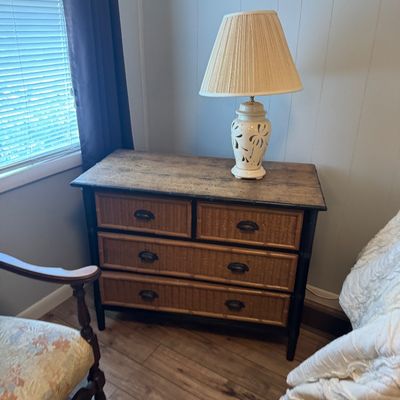 Tropical-style chest of drawers with wicker panel fronts and faux bamboo trim, topped with a cream ceramic table lamp.