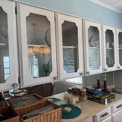 Built-in white painted hutch cabinet with glass-front doors, displayed dinnerware, and counter space.