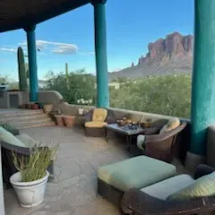 Sale Photo Thumbnail #46: Covered patio set with dark wicker armchairs, matching ottomans, and plush light cushions overlooking a mountain landscape.