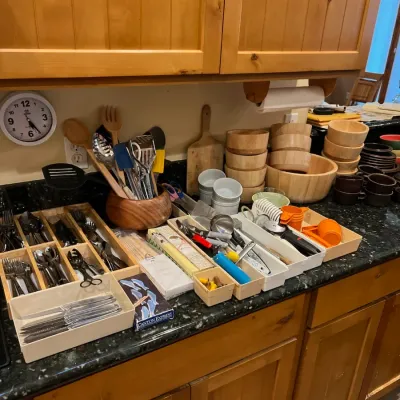 Sale Photo Thumbnail #20: Assorted kitchenware including wooden salad bowls, silverware, cooking utensils, and organizers displayed on a countertop.