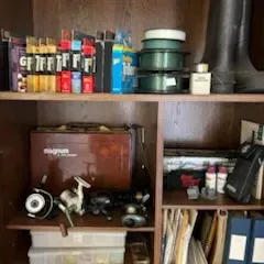 Sale Photo Thumbnail #36: Wooden shelving unit filled with fishing gear, including Plano Magnum tackle boxes, reels, spools of line, plastic utility organizers, and rubber boots.