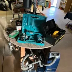 Sale Photo Thumbnail #40: Collection of power tools and household electronics, including a benchtop drill press, a Makita cordless tool set in a hard case, and a canister vacuum cleaner.