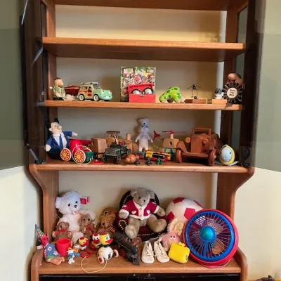 Sale Photo Thumbnail #11: Scandinavian modern teak hutch with smoked glass cabinet doors filled with vintage toys, wooden vehicles, and teddy bears.