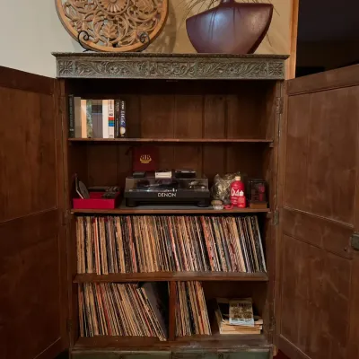 Sale Photo Thumbnail #47: Rustic carved wood armoire with distressed green trim, holding a Denon turntable, vinyl records, and VHS tapes.