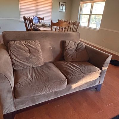 Sale Photo Thumbnail #150: Brown microfiber loveseat with button-tufted back detailing and matching accent pillows, set on dark wood feet.