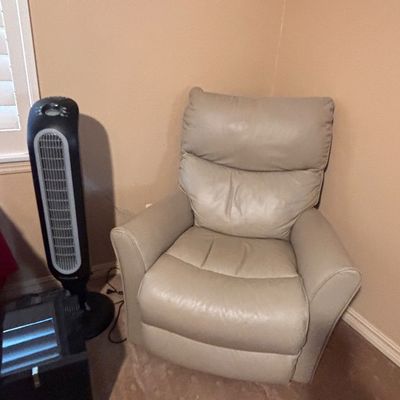 Sale Photo Thumbnail #80: Contemporary beige leather reclining armchair paired with a black Honeywell oscillating tower fan.