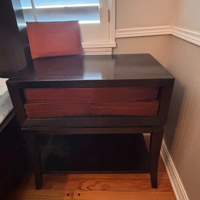 Sale Photo Thumbnail #88: Modern dark wood nightstand with contrasting reddish-brown drawers and a lower open shelf.